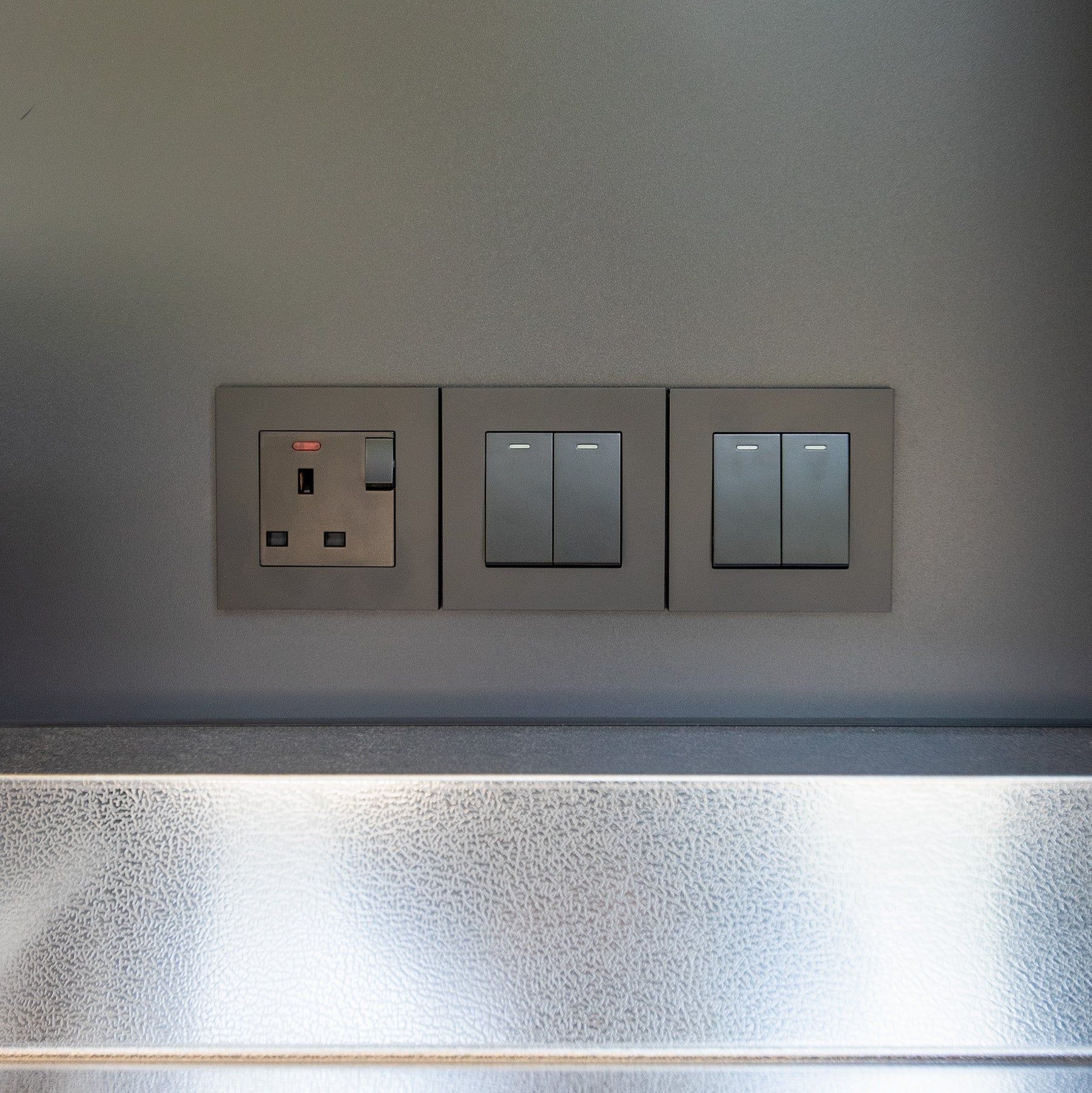 A double socket and two switch plates on the wall above an outdoor kitchen's worktop (supplier photograph)